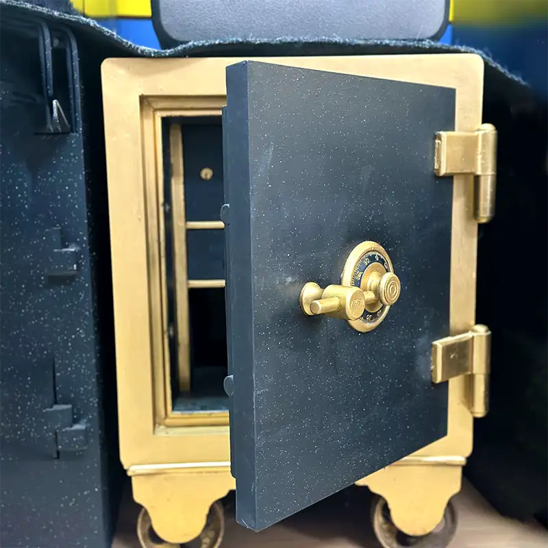 An golden coloured antique safe with a black door and golden handle