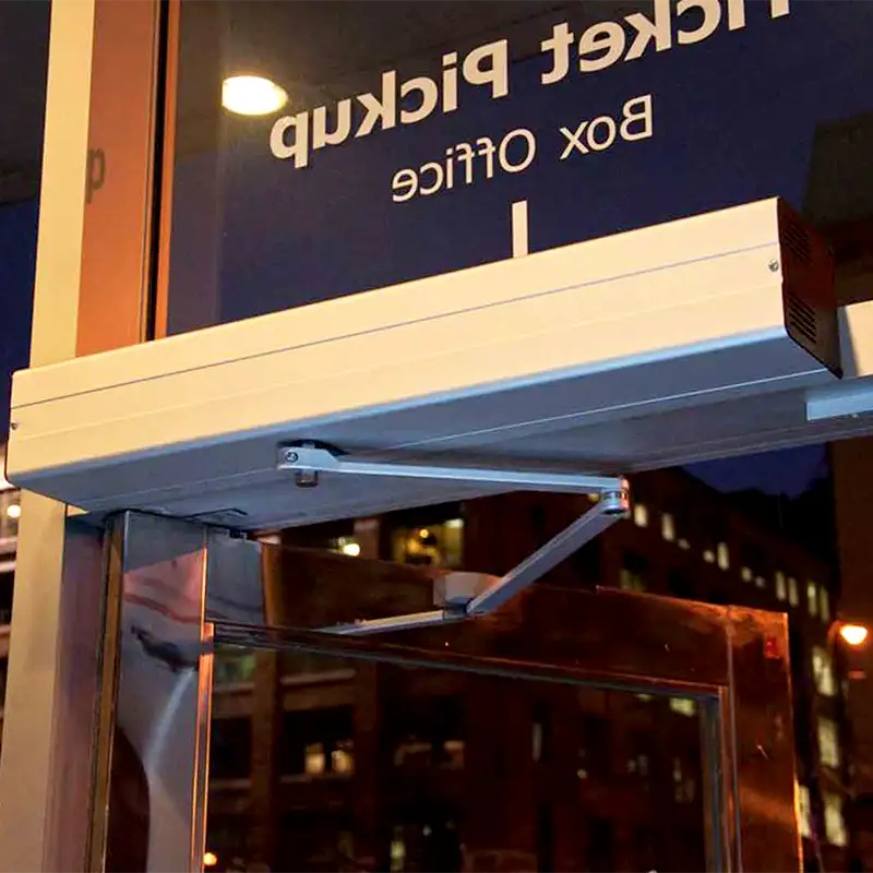 A large metal automatic door opener attached to a metal and glass door somewhere in Toronto